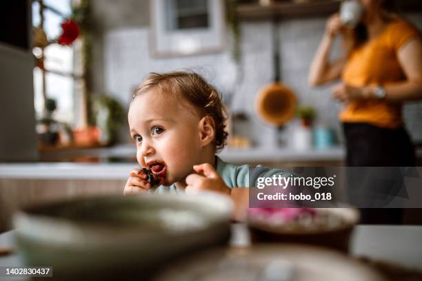 süßes kleines mädchen, das schokoladenkuchen in der küche isst. - food decoration stock-fotos und bilder