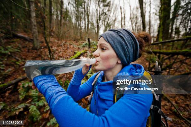a young active woman pauses to take a drink while hiking. - abbotsford canada stock pictures, royalty-free photos & images