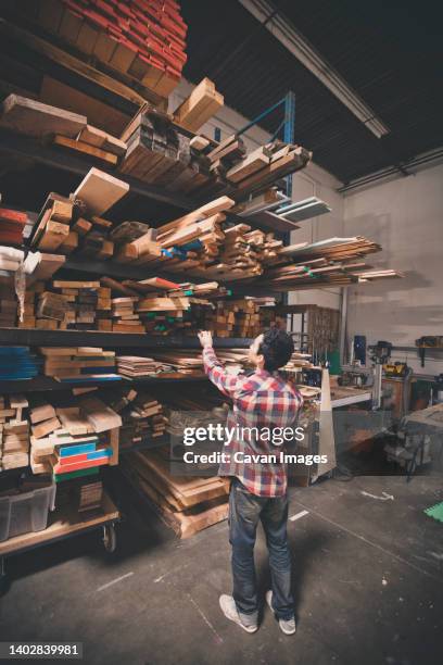 a carpenter surveys his wood rack for a piece of dimentional lumber. - dimentional stock-fotos und bilder