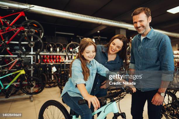 familie probiert neue fahrräder im fahrradladen aus - shopping with bike stock-fotos und bilder