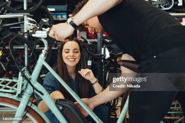 mann zeigt dem kunden neues e-bike im fahrradladen - shopping with bike stock-fotos und bilder