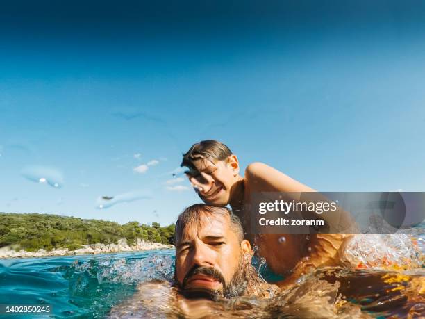 junge, der mit seinem vater spielt und versucht, ihn unter wasser zu drücken, aufgenommen mit einer wasserdichten kamera - drowning stock-fotos und bilder