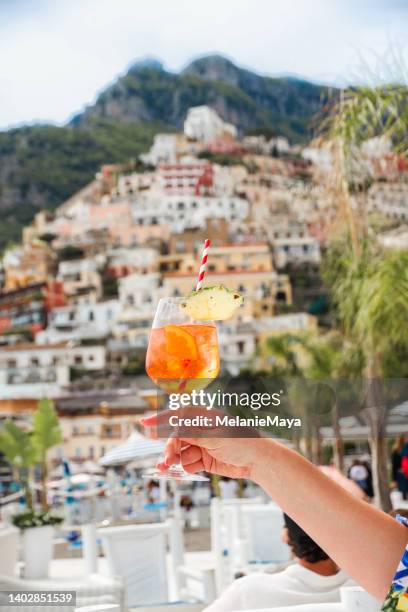ポジターノイタリア海岸の風景で食前酒カクテルアペロ�ールスプリッツヴェネツィアーノを握る手 - アマルフィ海岸 ストックフォトと画像