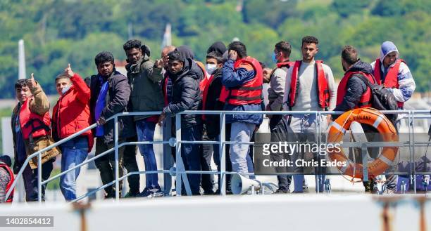 Migrants wave and gesture as the arrive in port on Border Force boat Valiant after attempting the crossing of the English Channel from France on June...