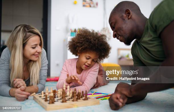 little multiracial girl with mother and father playing chess at home. - kids playing chess stock pictures, royalty-free photos & images