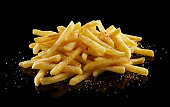 Pile of delicious fried potatoes with salt against black background