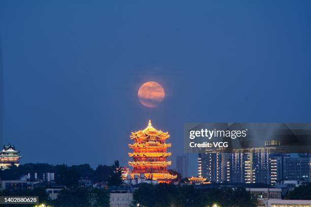 The full moon rises over the Yellow Crane Tower on June 14, 2022 in Wuhan, Hubei Province of China.