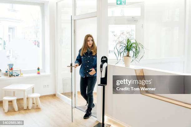 young woman walking into dental surgery for check up - krankenhaus eingang stock-fotos und bilder