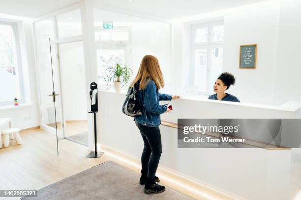customer talking to dental practice receptinoist - dentist office sign stock pictures, royalty-free photos & images