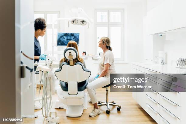 dentist looking at x-ray with patient in surgery - cabinet dentaire photos et images de collection