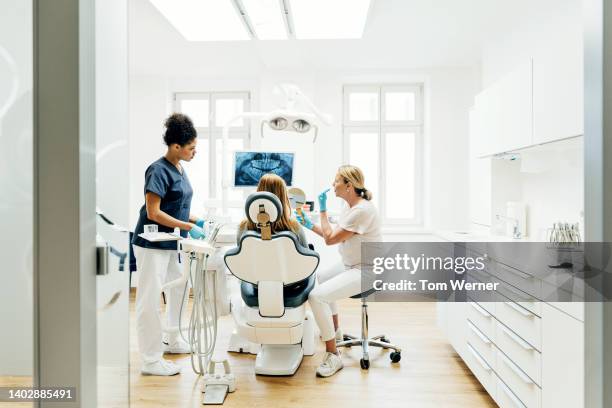 orthodontist showing patient x-ray of teeth in surgery - dentista foto e immagini stock