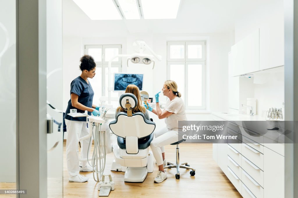 Orthodontist Showing Patient X-Ray Of Teeth In Surgery