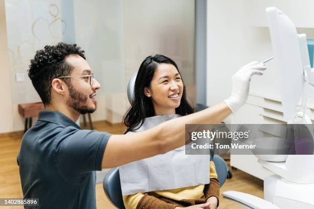 young patient talking to dentist about dental health during checkup - dentist office foto e immagini stock