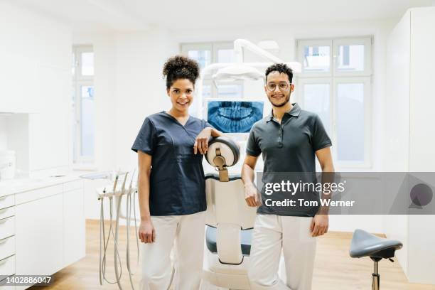 portrait of dentist and dental assistant in well lit surgery - sprechstundenhilfe stock-fotos und bilder