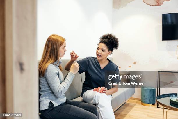 young woman looking at example of braces with dental technician - sensitivity in tooth stock-fotos und bilder