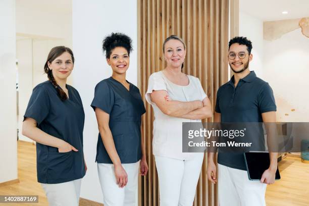 portrait of staff together in family dental practice - navy blue interior stock pictures, royalty-free photos & images