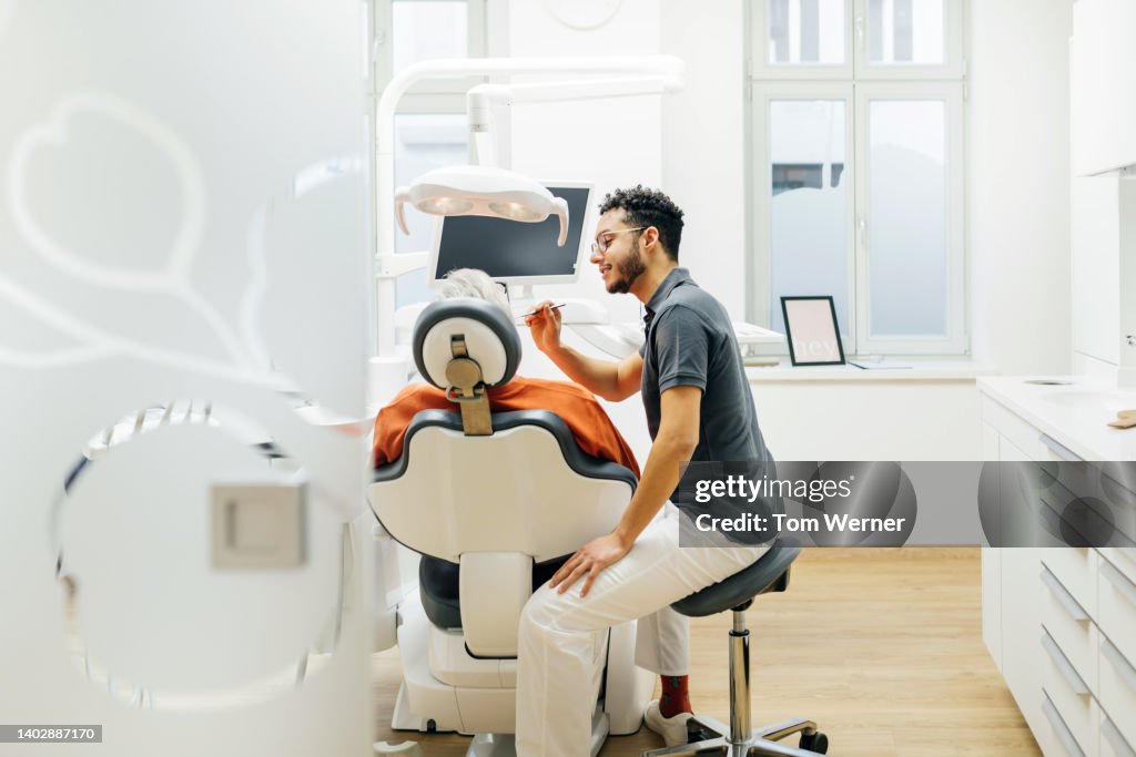 Dentist Leaning In While Tending To Patient In Surgery