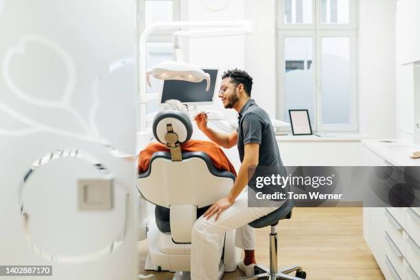 dentist leaning in while tending to patient in surgery - dental health photos et images de collection