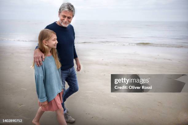 mature man and girl walking on the beach - granddaughter ストックフォトと画像