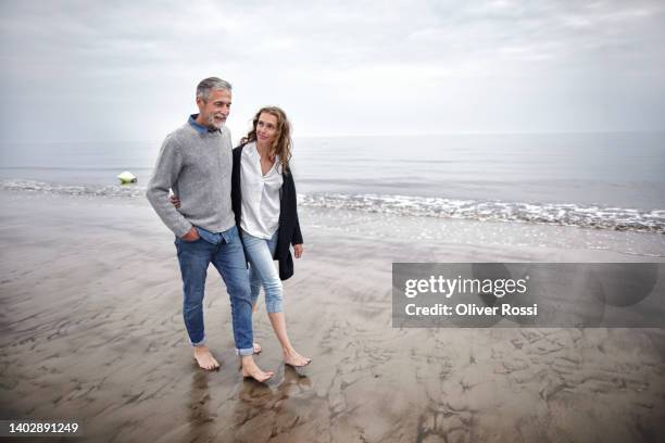 father and adult daughter walking on the beach - overcast beach stock pictures, royalty-free photos & images