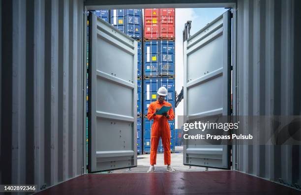 foreman control loading containers box from cargo freight ship for import export - abbigliamento antinfortunistico foto e immagini stock