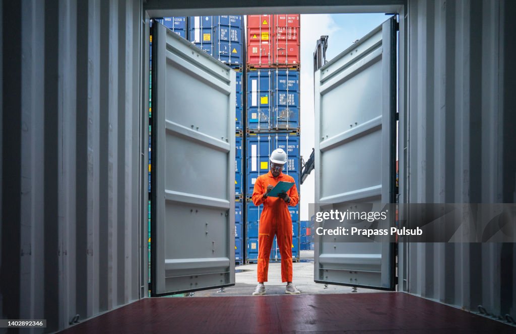 Foreman control loading Containers box from Cargo freight ship for import export