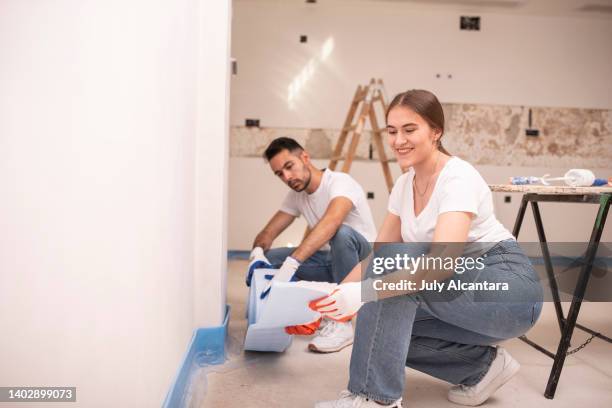 pair of renovation workers measure the insulation and compare it with the one already in place to preserve the wall, woman at work - wainscoting stock pictures, royalty-free photos & images