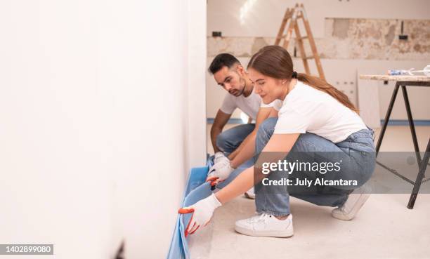 un par de trabajadores de renovación miden el aislamiento y lo comparan con el que ya está en su lugar para preservar la pared. - aislante fotografías e imágenes de stock