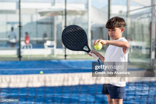 little boy playing paddle tennis in court - bat stockfoto's en -beelden