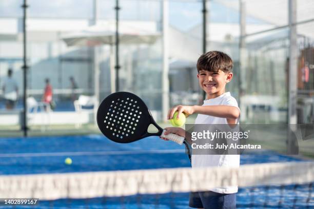 niño pequeño jugando al pádel en la cancha, sonriendo listo para servir - pala de tenis de mesa fotografías e imágenes de stock