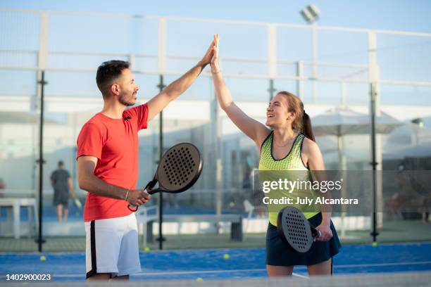 couple playing paddle tennis in court, hi five fair play gesture - friendly match stock pictures, royalty-free photos & images