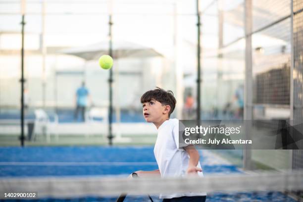 little boy playing paddle tennis in court, sport class. shoting ball - pudel stock pictures, royalty-free photos & images