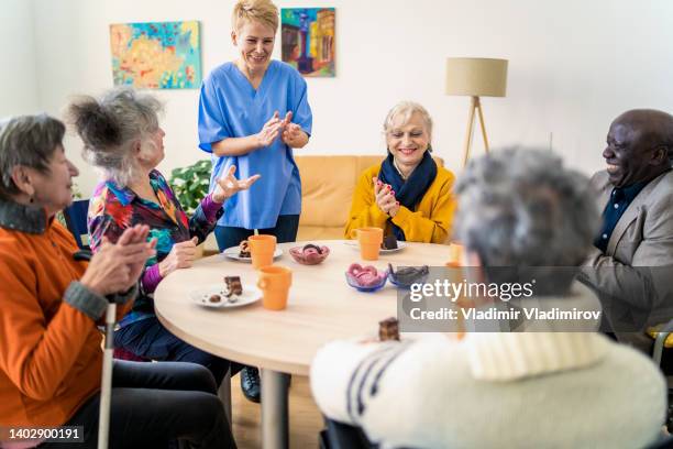 lächelnde bewohner mit ihrem betreuer - residential care stock-fotos und bilder