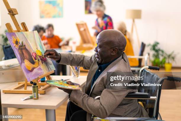 senior african-american man painting - elderly cognitive stimulation therapy stockfoto's en -beelden