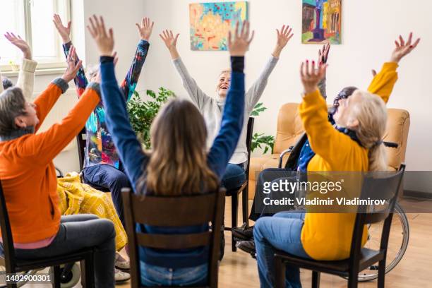 a therapy group with their arms in the air sitting in a circle - healing prayer images stock pictures, royalty-free photos & images