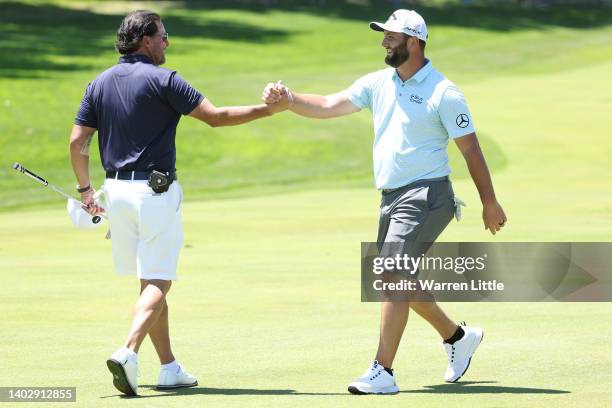 Phil Mickelson of the United States congratulates Jon Rahm of Spain after Rahm holed a shot for eagle on the fourth hole during a practice round...
