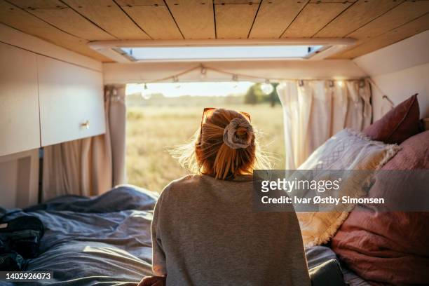 woman looking at the view from the back of a camper van - escapismo imagens e fotografias de stock