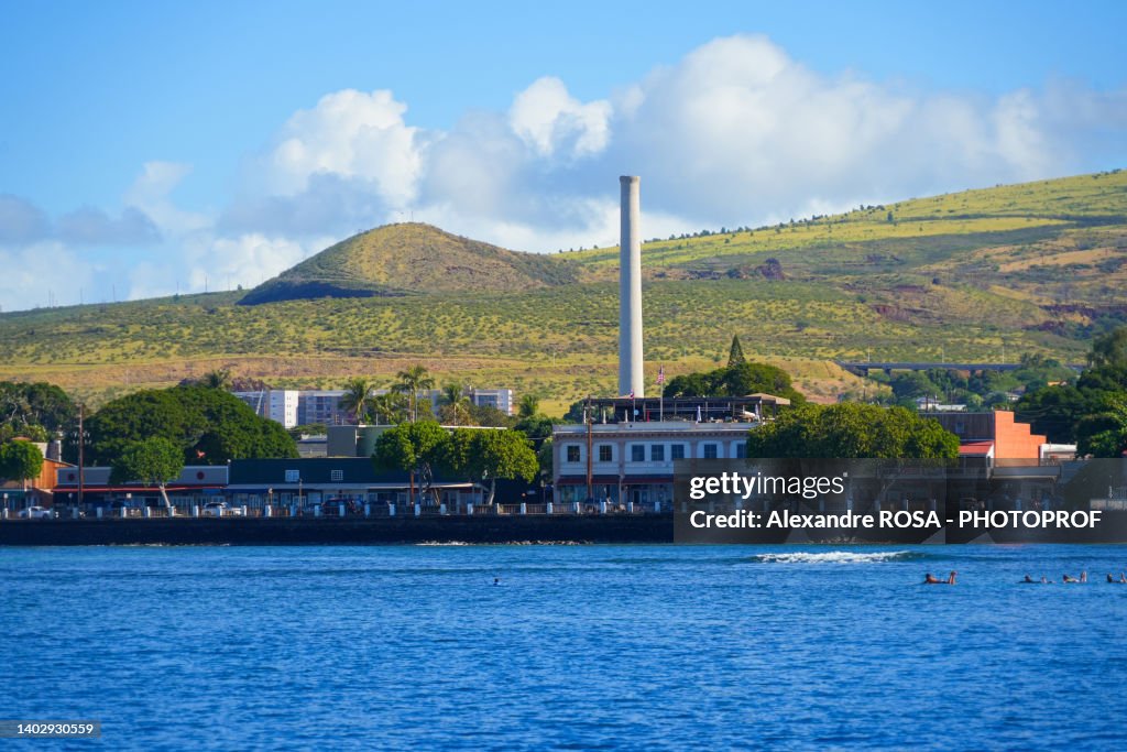 Lahaina old city center seen from the Pacific Ocean in front of the green slopes of the West Maui Nature Reserve - Brick buildings with a chimney west of Maui island in Hawaii