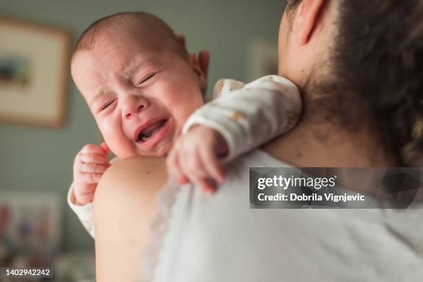 primo piano di un bambino esausto che piange tra le braccia della madre - complaining foto e immagini stock