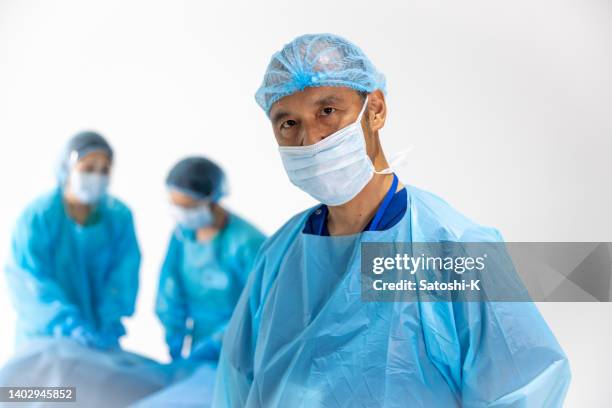 portrait of male surgeon, other surgeons working at the background - operating gown stock pictures, royalty-free photos & images