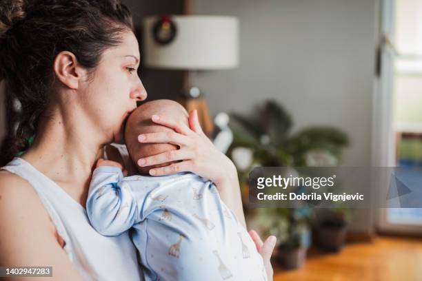 woman kissing her baby's head - tired mother stock pictures, royalty-free photos & images