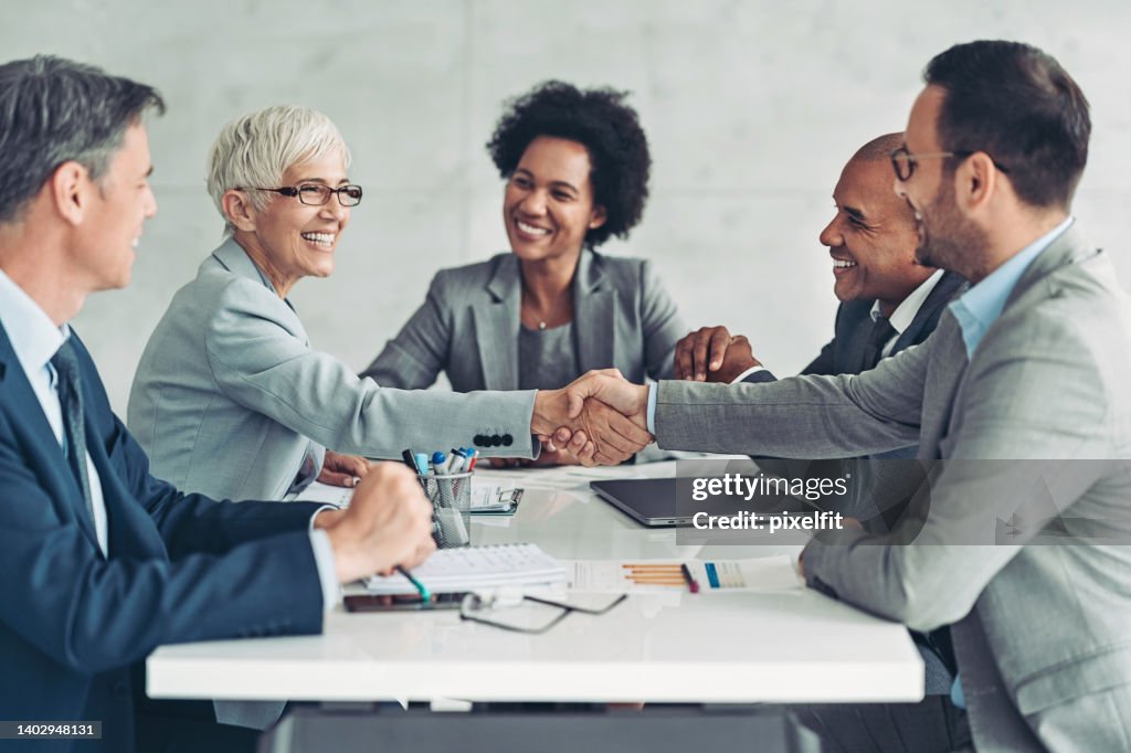 Businesswoman and businessman shaking hands across the table