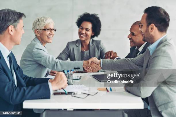 empresária e empresário apertando as mãos em toda a mesa - shaking hands - fotografias e filmes do acervo