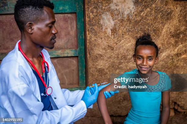 doctor is doing an injection to young african girl in small village, east africa - vaccine africa stock pictures, royalty-free photos & images