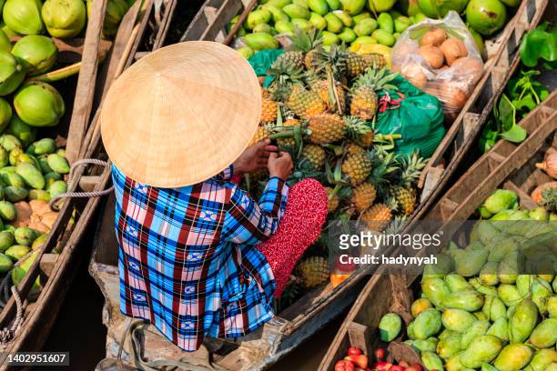 femme vietnamienne vendant des fruits sur le marché flottant, delta du fleuve de mékong, vietnam - mekong delta photos et images de collection