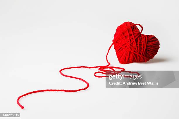 red heart-shaped wool ball unraveling - frayed stock-fotos und bilder