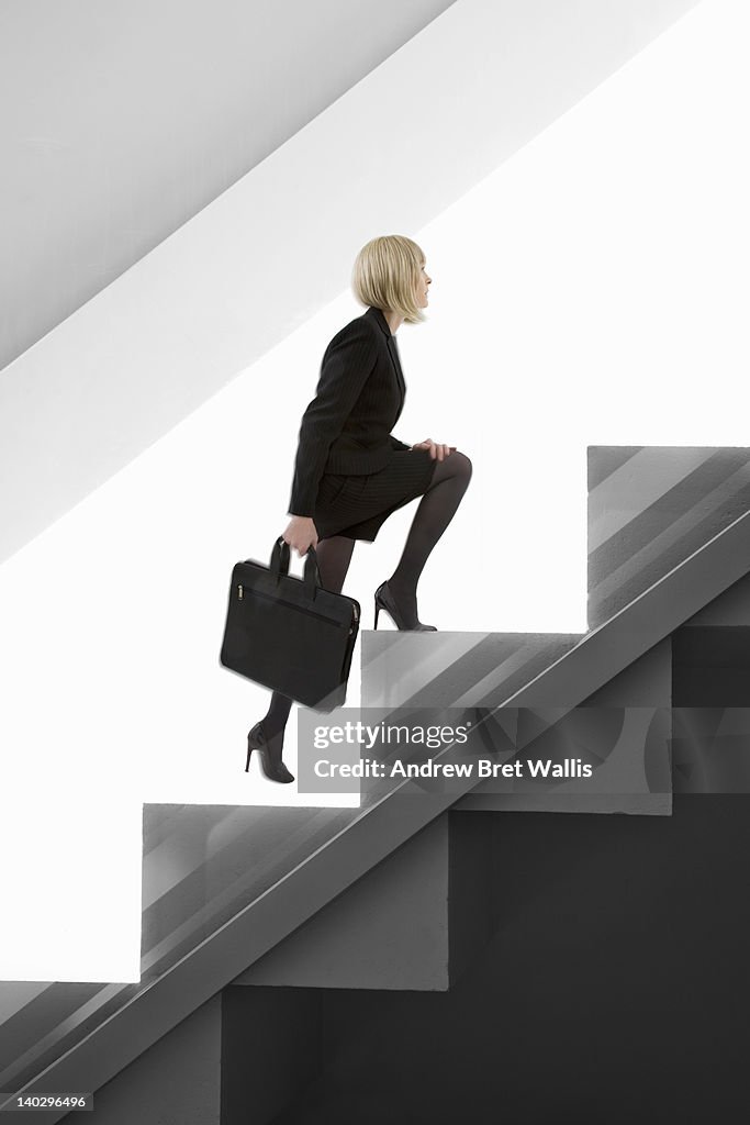 Little businesswoman climbs giant stairs