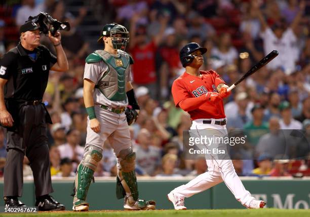 Rafael Devers of the Boston Red Sox watches his three run home run in the fourth inning inning as Sean Murphy of the Oakland Athletics and home plate...