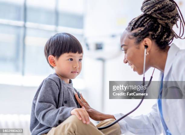 listening to a little boys heart - doctor with child stockfoto's en -beelden