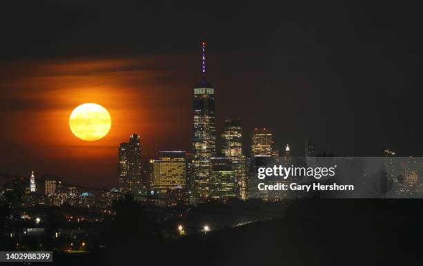 The full Strawberry Supermoon rises behind lower Manhattan and One World Trade Center in New York City on June 14 as seen from North Arlington, New...